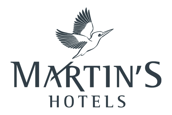 Logo for Martins Hotels featuring a bird in flight above the stylized text Martins Hotels in dark, elegant font on a light background. The bird’s tail, reminiscent of an audiovisual wave, forms part of the letter A.